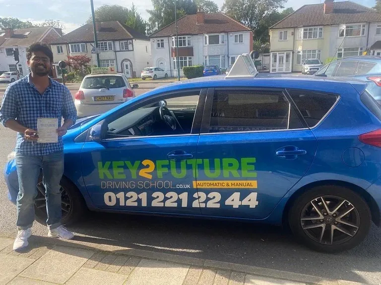 A Key2Future student holding their pass certificate beside a branded tuition car